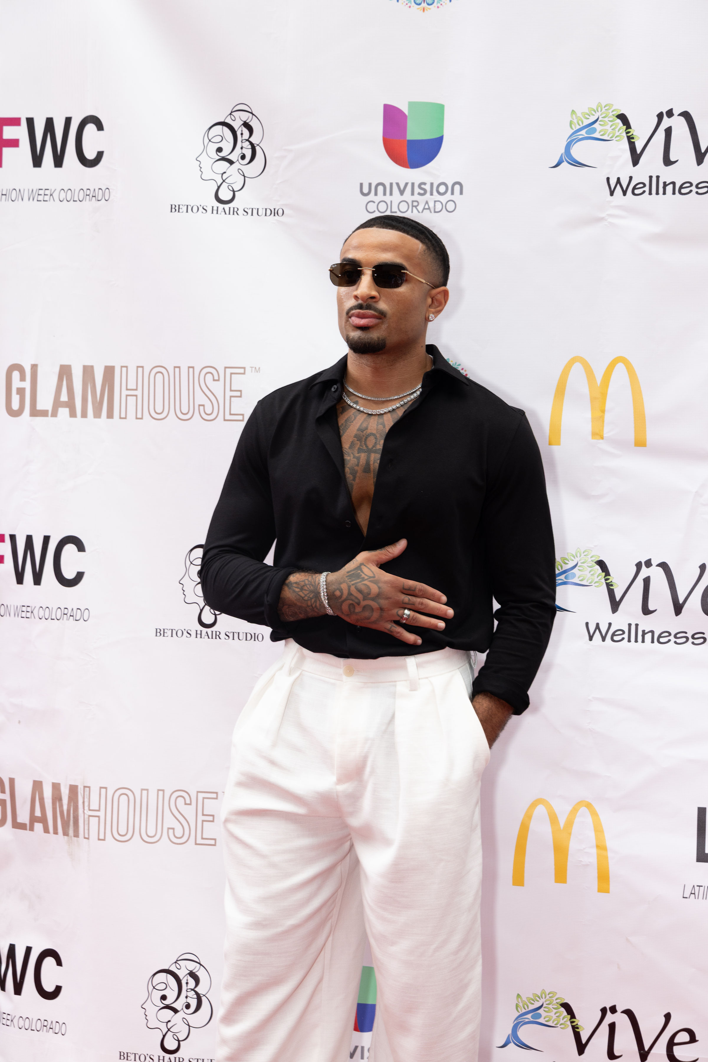 James Muhammad at Latin Fashion Week Colorado red carpet in black shirt and white trousers