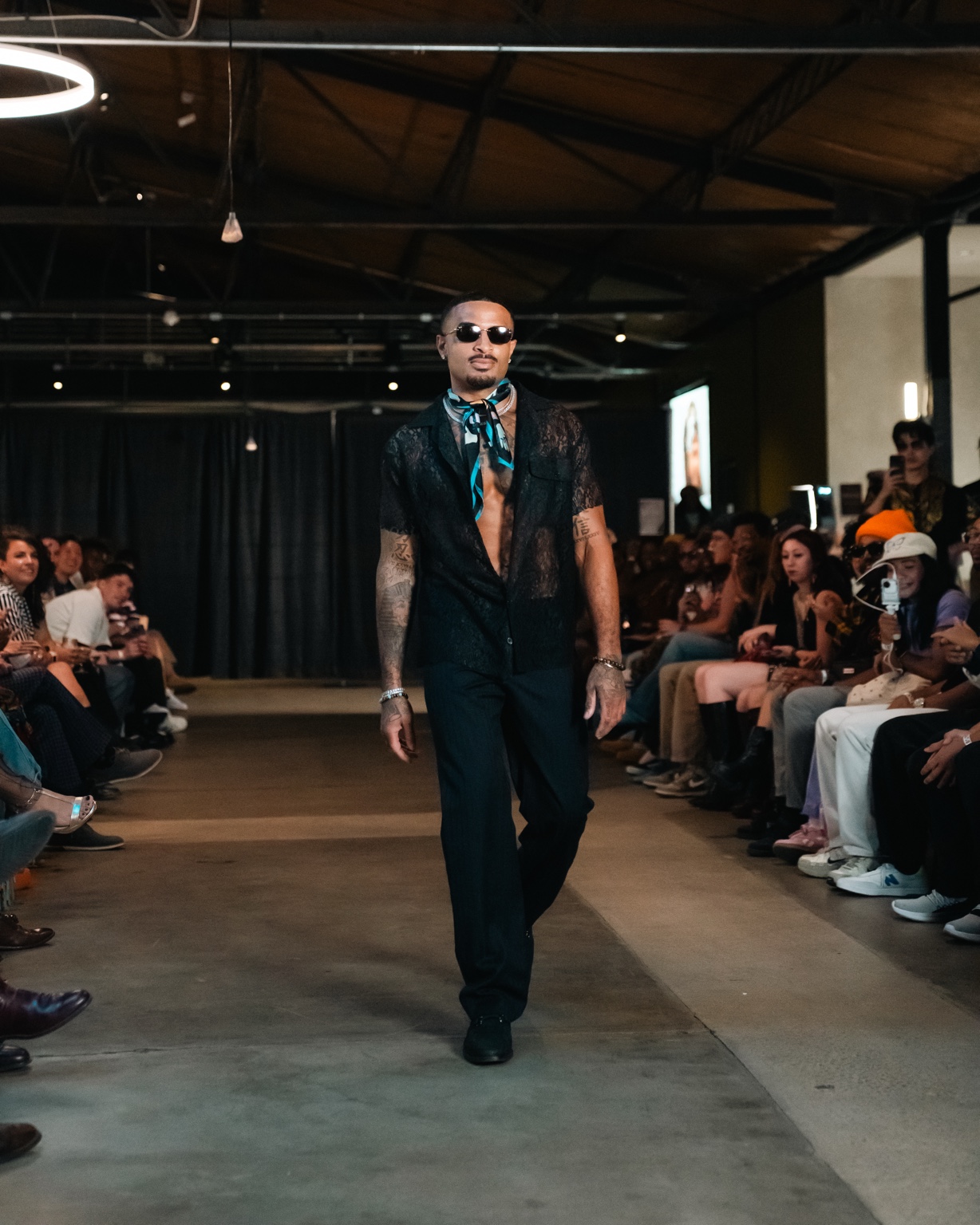 James Muhammad walking the runway in black lace shirt and scarf